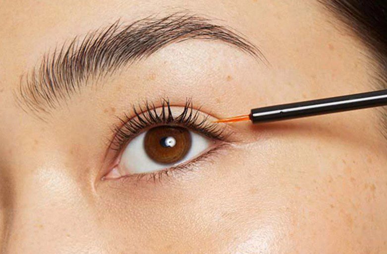 An image of a woman applying lash serum