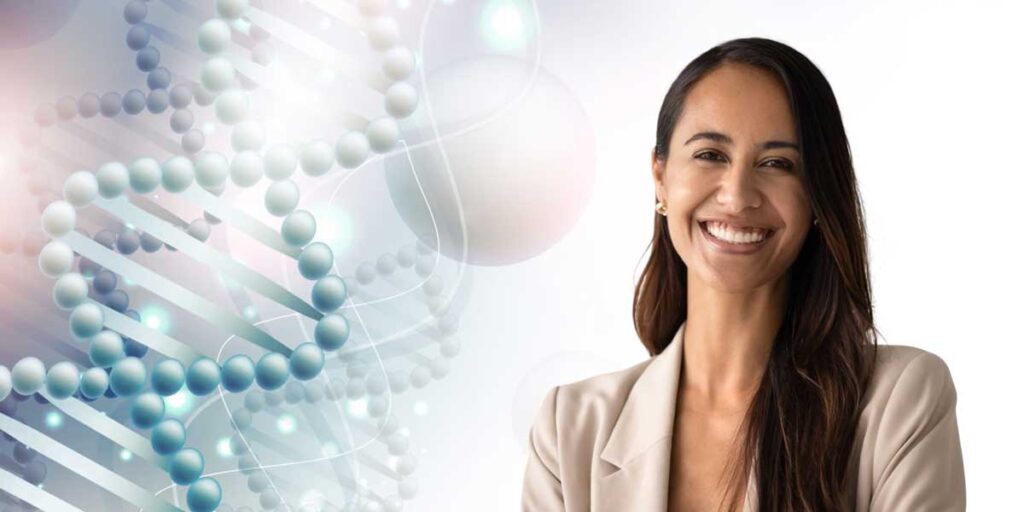 A woman dressed in a beigh suit with long brown hair smiling against a backdrop of a DNA illustration