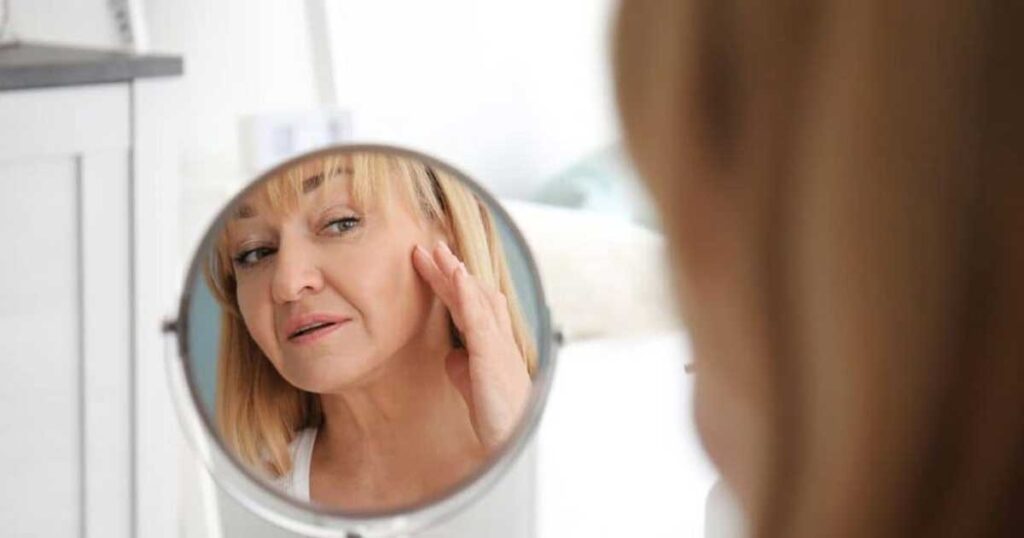 A woman looking in the mirror at her skin that needs a skin tightening treatment in Scottsdale